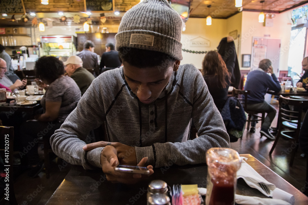 Fototapeta premium A young man looks at his phone while waiting for his meal
