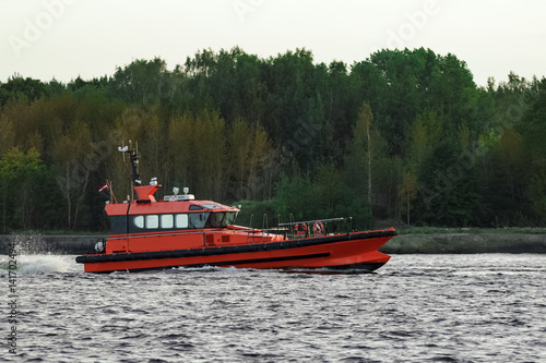 Orange pilot ship sailing on the Daugava river