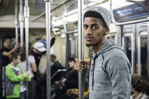 A tired, young african american man rides the NYC subway