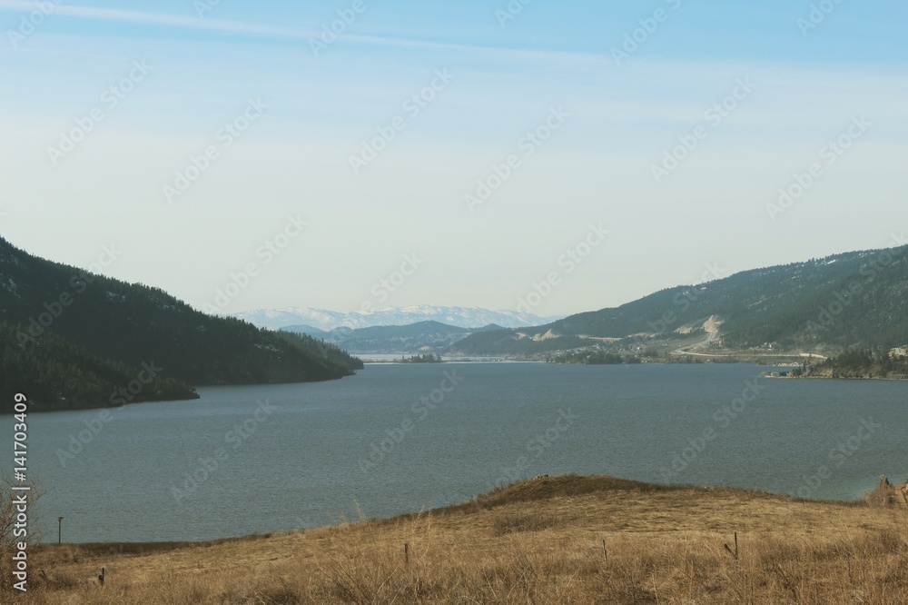 Grassy field overlooking lake and mountains