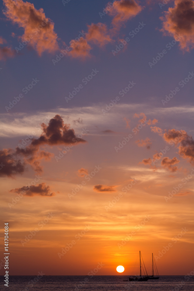 The cloudy sunset and sailing boats. The boats sailing in the ocean in sunset lights. Vertical outdoors shot.