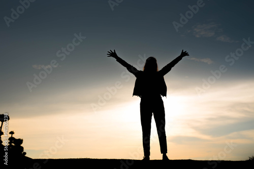 woman silhouette standing raise hand on sunset