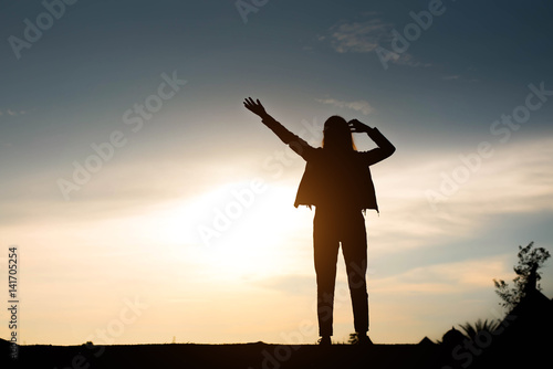woman silhouette standing raise hand on sunset