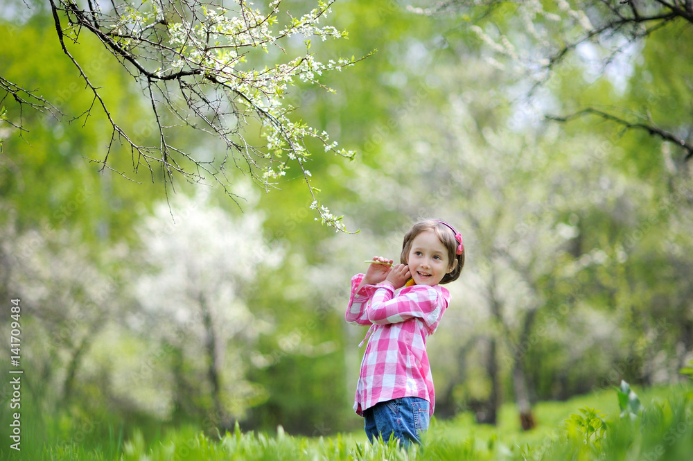 Adorable little girl having fun in blooming cherry garden on beautiful spring day Adorable little girl having fun in blooming cherry garden on beautiful spring day