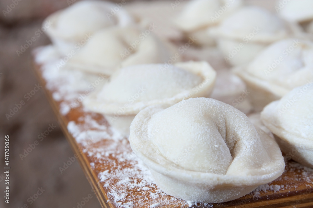 Process of making homemade pelmeni (dumplings) on wooden board - traditional dish of Russian cuisine. Selective focus Process of making homemade pelmeni (dumplings) on wooden board - traditional dish of Russian cuisine. Selective focus