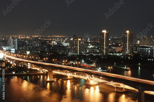 night picture of car crossing bridge in Bangkok over Chao Phraya River with slow shutter speed  © Uthaipat