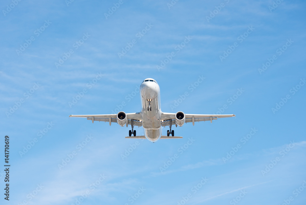 Obraz premium Commercial airplane flying in blue sky, full flap and landing gear extended
