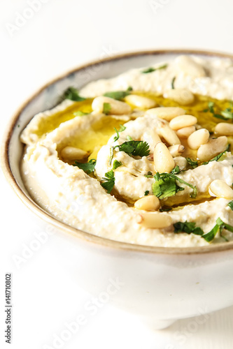 Classic hummus with herbs, olive oil in a vintage ceramic bowl. Traditional Middle Eastern cuisine. Light white background.
