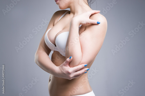 Fototapeta Woman in white push up bra on gray background, perfect female breast