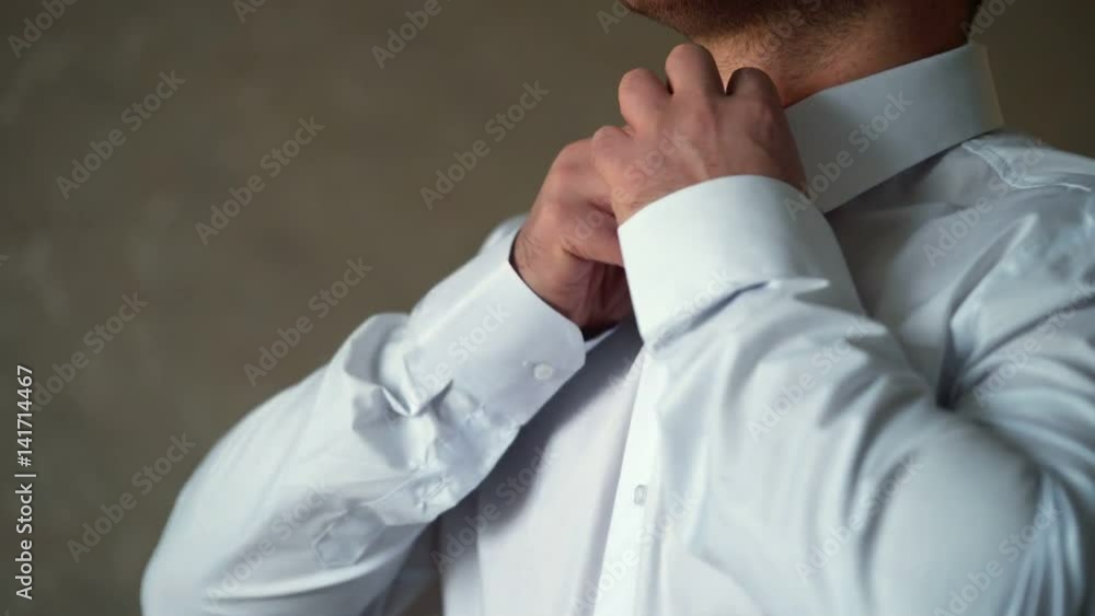Unrecognizable young man buttoning white shirt Unrecognizable young man buttoning white shirt