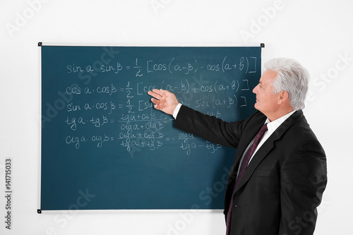 Senior teacher writing on b...