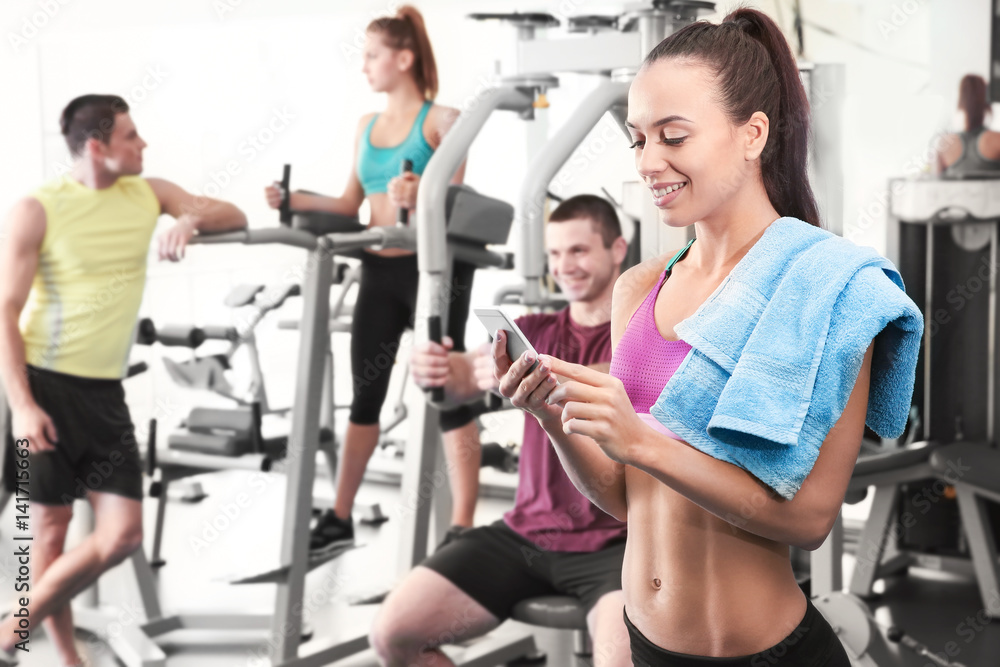 Young woman with cellphone in gym