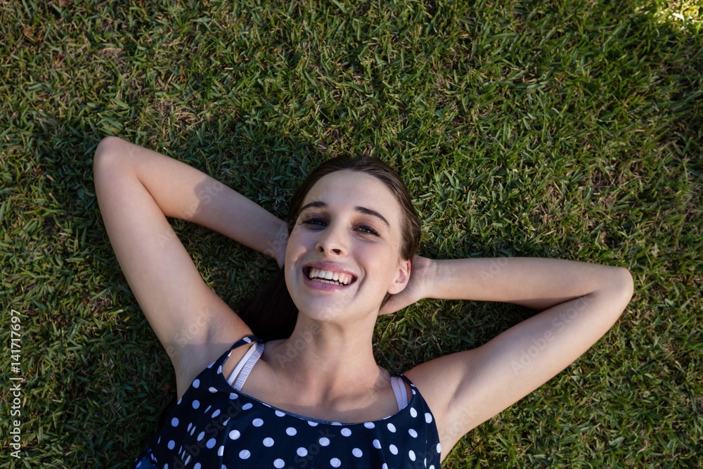 Smiling woman lying on grass with hands behind head Smiling woman lying on grass with hands behind head