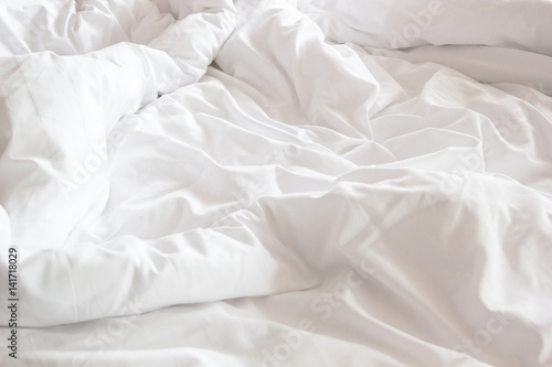 wrinkle messy blanket and white pillow in bedroom after waking up in the morning, from sleeping in a long night, details of duvet and blanket, an unmade bed in hotel bedroom with white blanket.