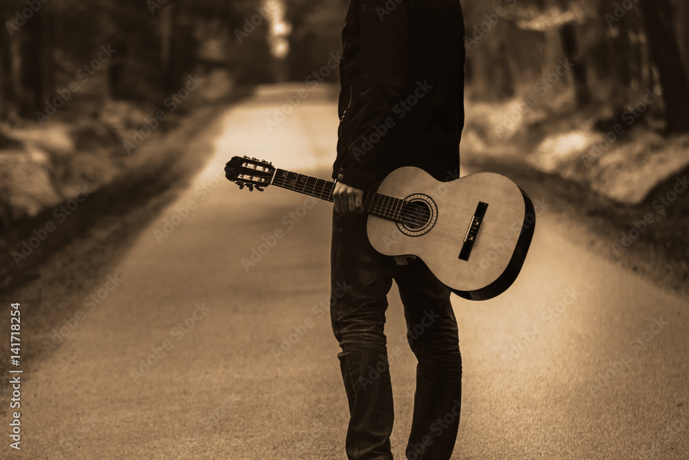 Obraz premium Osoba na ścieżce z gitarą. Bezpłatne podróżowanie z instrumentem country w lesie.