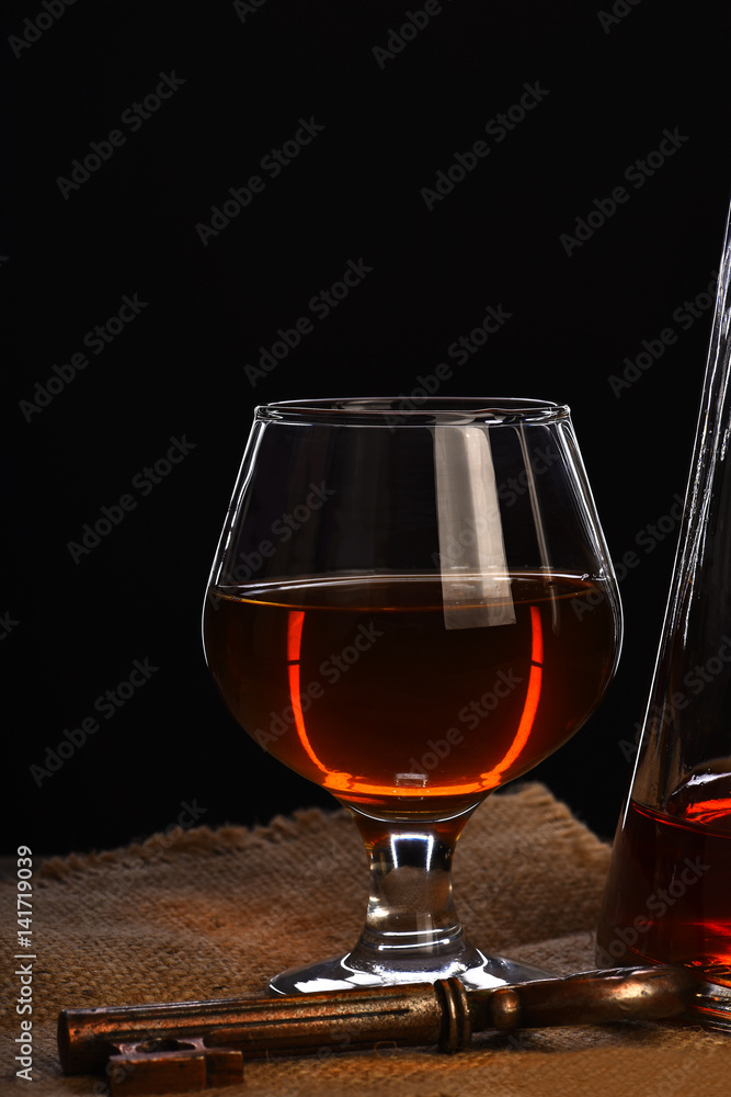glass, carafe with cognac, whiskey and key on wooden table glass, carafe with cognac, whiskey and key on wooden table