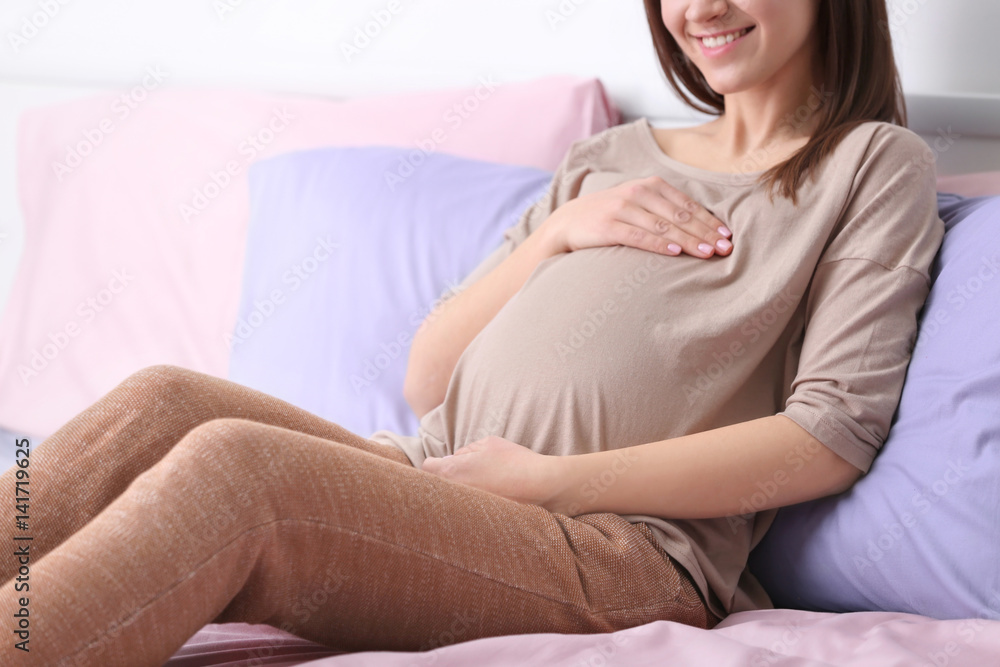 Beautiful pregnant woman resting on bed at home