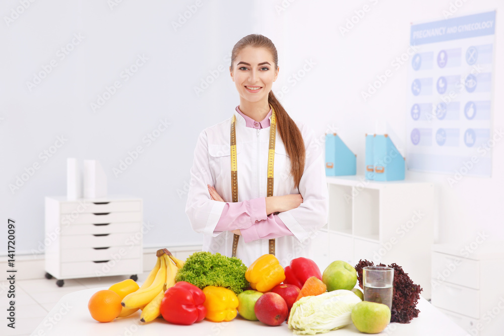 Young female nutritionist with vegetables and fruits in her office Young female nutritionist with vegetables and fruits in her office