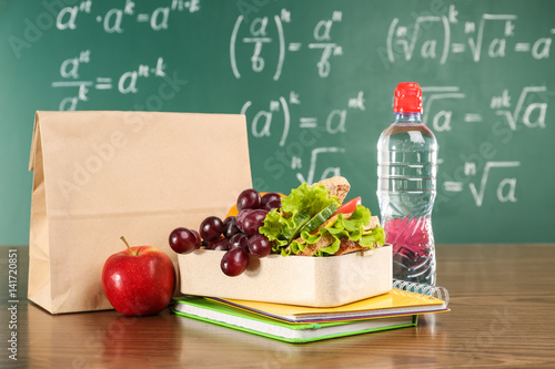 Lunch bag on wooden table against chalkboard background