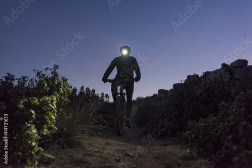 Cyclist descends the hill at night lit by lantern