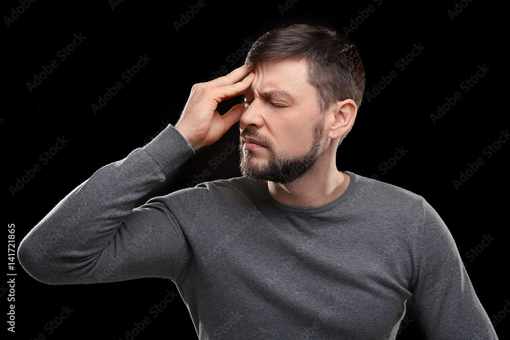 Handsome young man suffering from headache on dark background Handsome young man suffering from headache on dark background