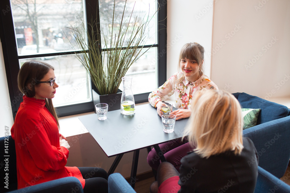 Three young ladies sitting by table Three young ladies sitting by table