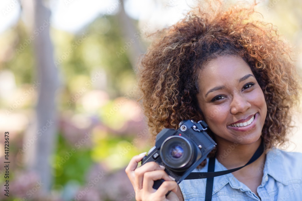 Smiling woman standing with digital camera Smiling woman standing with digital camera