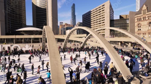 Circa Family Day 2017, Pan of People Ice Skating on Rink at City Hall in Toronto on Sunny and Warm February Day photo