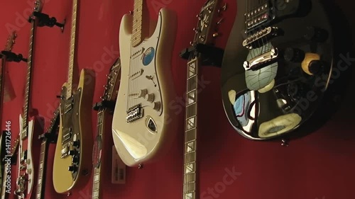 A guitar shop with many electric guitars. Camera pans in.

