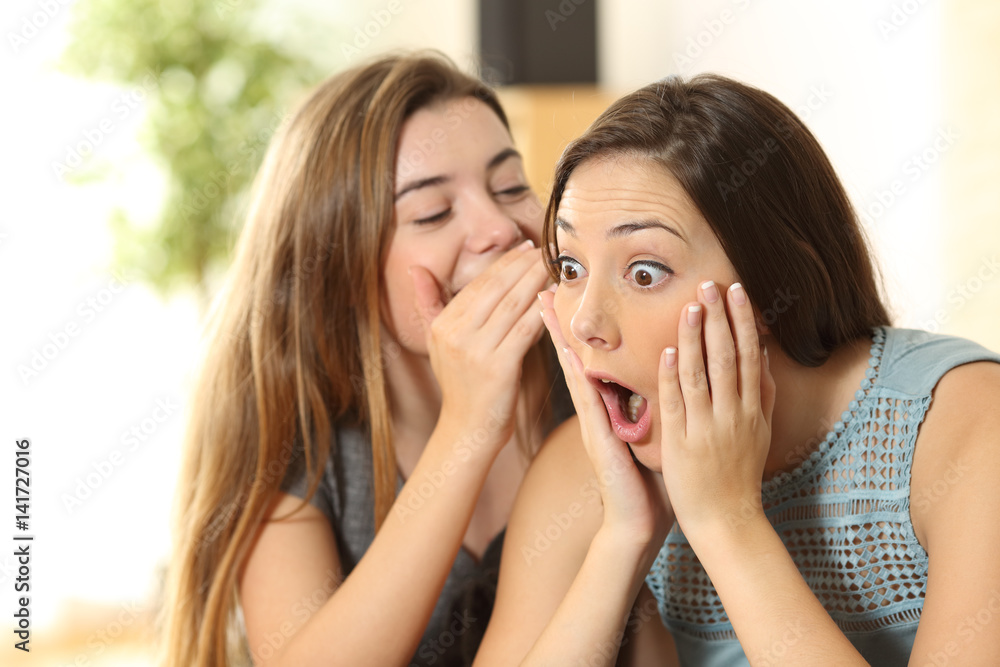 Girl telling secrets to her amazed friend Girl telling secrets to her amazed friend