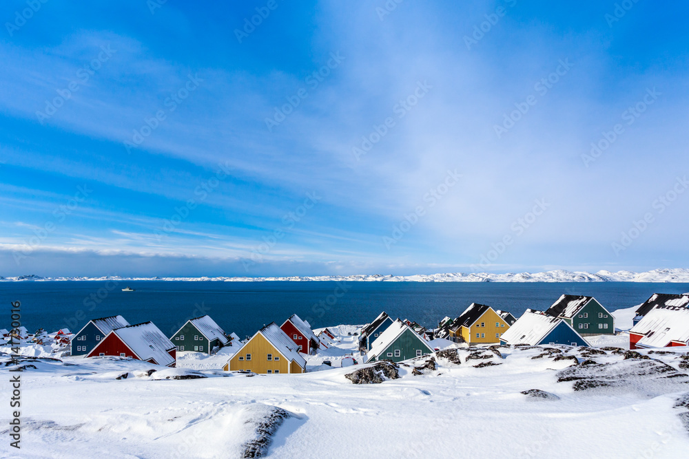 Yellow, blue, red and green inuit houses covered in snow at the fjord of Nuuk city, Greenland - obrazy, fototapety, plakaty 