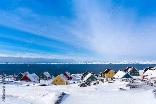 Yellow, blue, red and green inuit houses covered in snow at the fjord of Nuuk city, Greenland