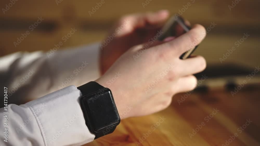 Close up shot of a business woman hands, who uses a smartphone and a smart watches to work on her new project. A woman flips through the web pages to find new sites for the sale of ideas. Close up shot of a business woman hands, who uses a smartphone and a smart watches to work on her new project. A woman flips through the web pages to find new sites for the sale of ideas.