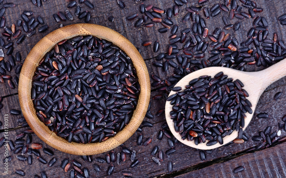 Fototapeta premium Black rice in a bowl and spoon on table