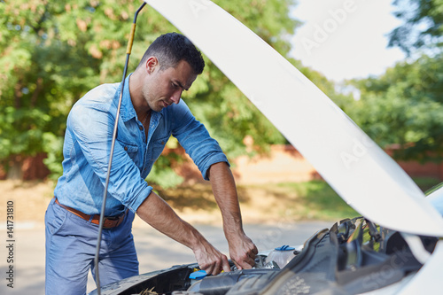 Stressed man repairing a broken car on the road