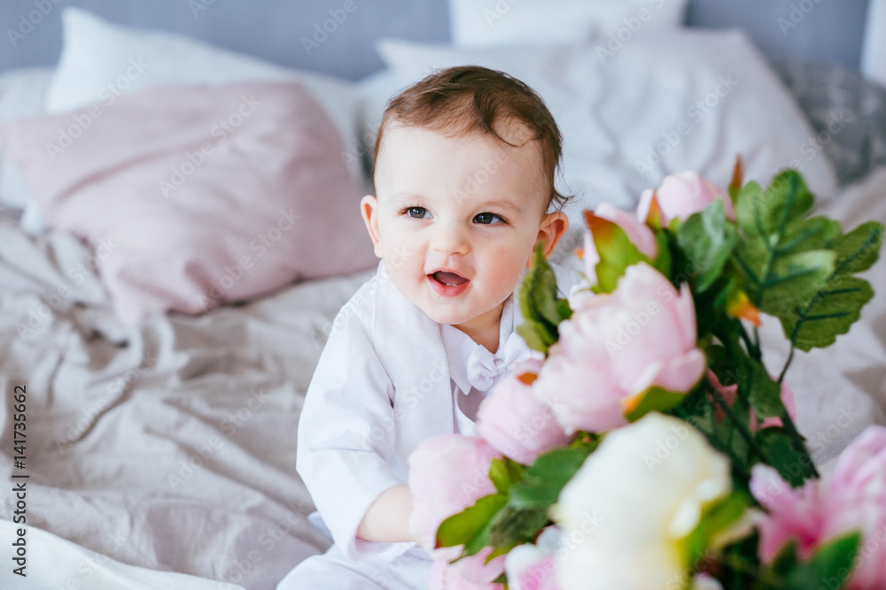 The tenderness boy with flowers sitting on the bed The tenderness boy with flowers sitting on the bed