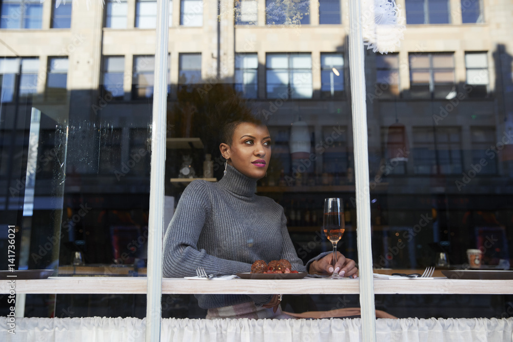 Stylish young woman sitting in cafe seen through window Stylish young woman sitting in cafe seen through window