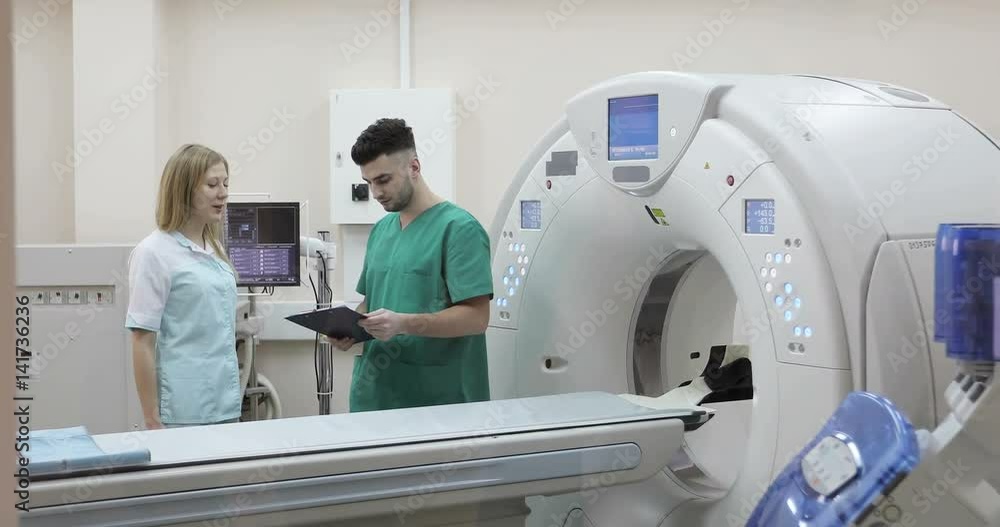 4K Young doctor and nurse discussing diagnosis on a background of a new magnetic resonance imaging. 4K Young doctor and nurse discussing diagnosis on a background of a new magnetic resonance imaging.