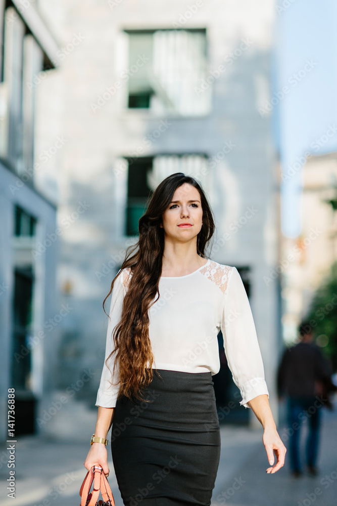 Confident young lady walking down street