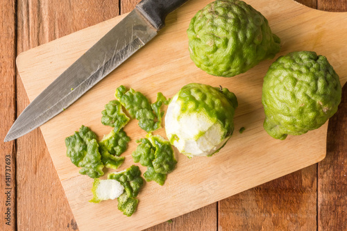 Sliced skin bergamot or kaffir lime with knife on wooden table background.