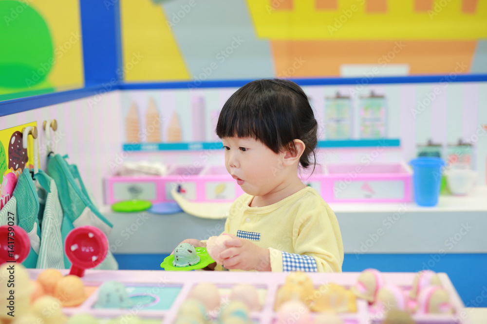 Little girl playing pretend as a sale in ice-cream shop Little girl playing pretend as a sale in ice-cream shop