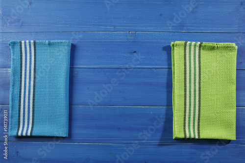 Blue wooden picnic table with green and blue dishcloth on