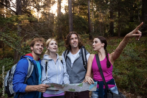 Quadro su tela Group of friends holding a map and looking forward while hiking
