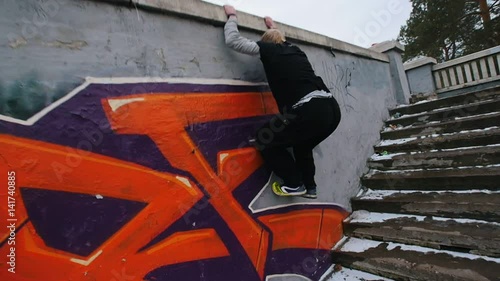 Urban city parkour - slow motion jumping - athlete performing free-running in winter park photo