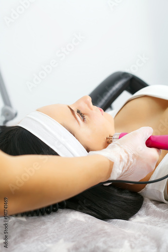 Cosmetician performing photorejuvenation cosmetology procedure for a woman