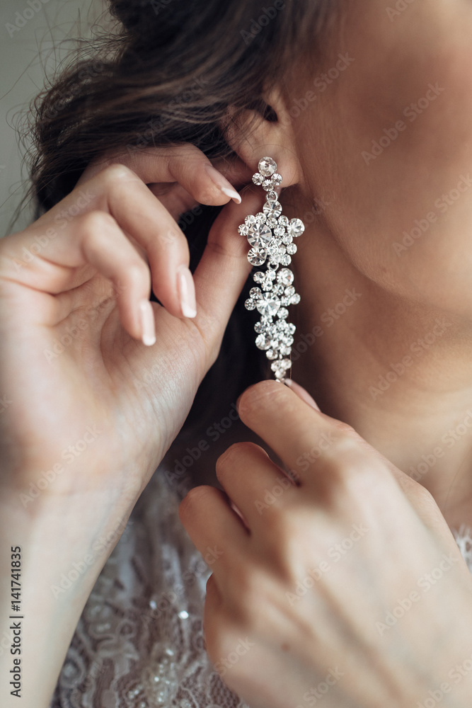 Close-up of crystal earring in bride's fingers
