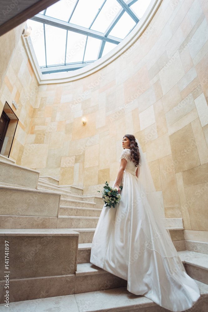 Obraz premium Bride in dress with long train walks up in a marble room