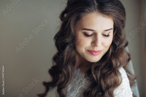Bride with long silky hair waves closes her eyes leaning to the shoulder