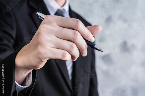 Close up of businessman hand holding pen on grunge background.
