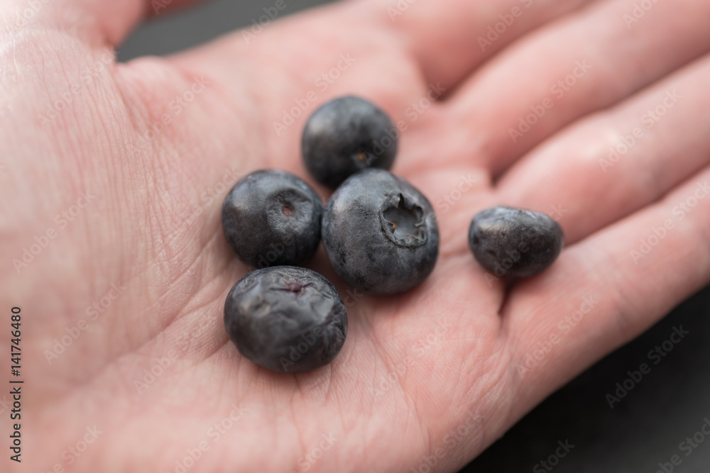 Natural looking blueberries in human hand. Selective focus.